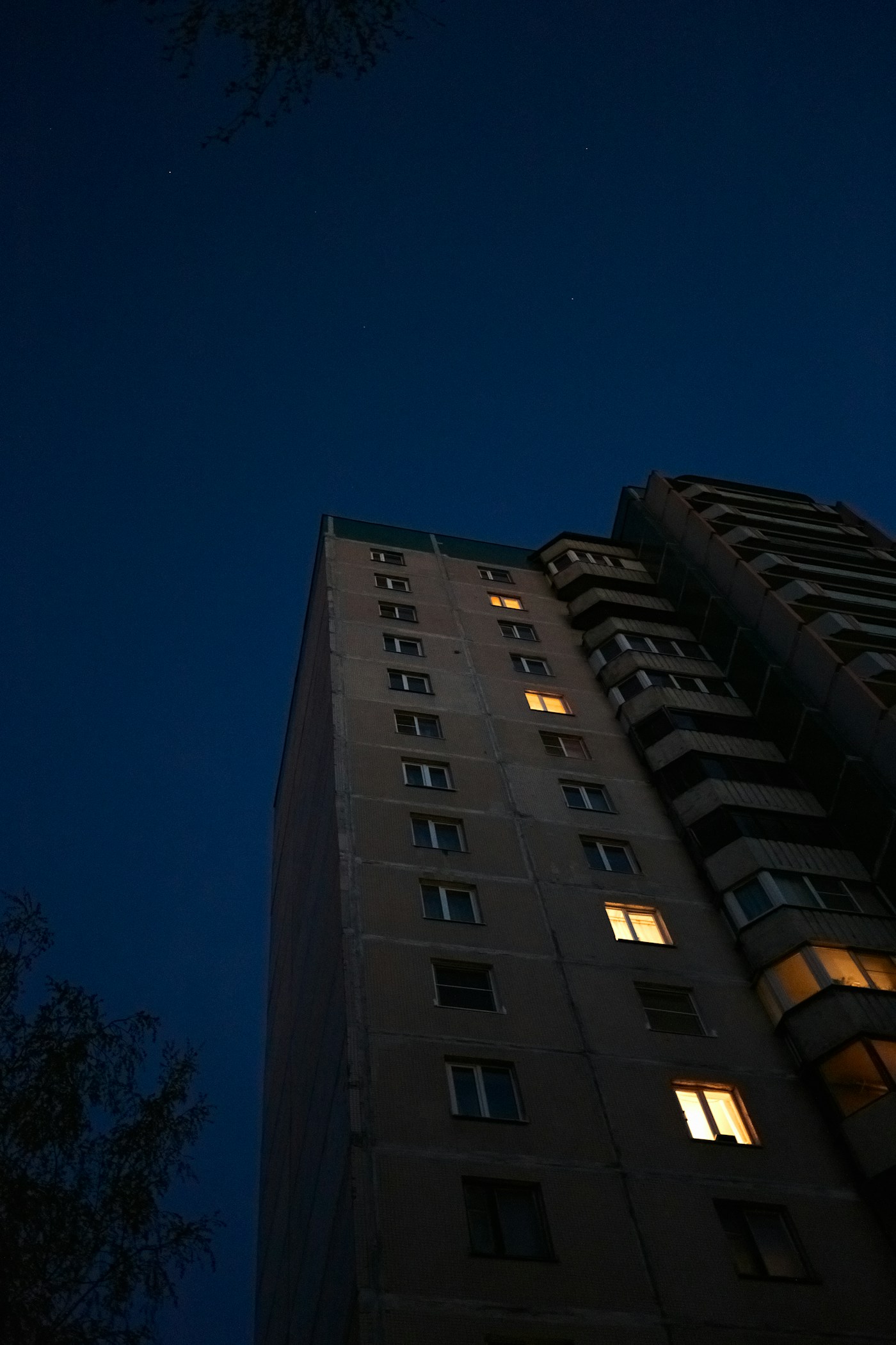 Edifício residencial ao anoitecer com janelas acesas